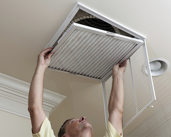 Senior man opening air conditioning filter in ceiling